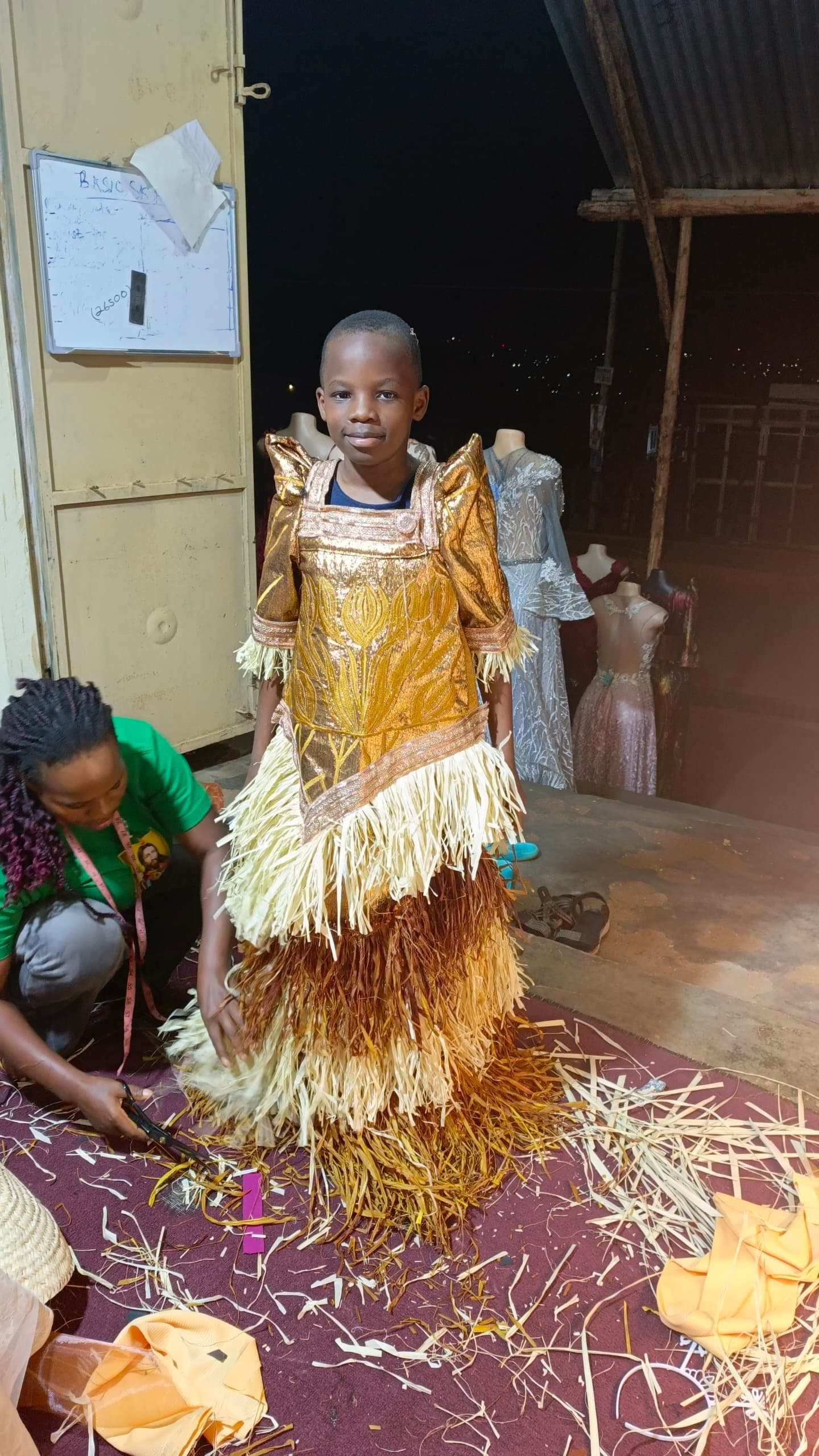 A boy in an ornate gold costume having final touches added backstage