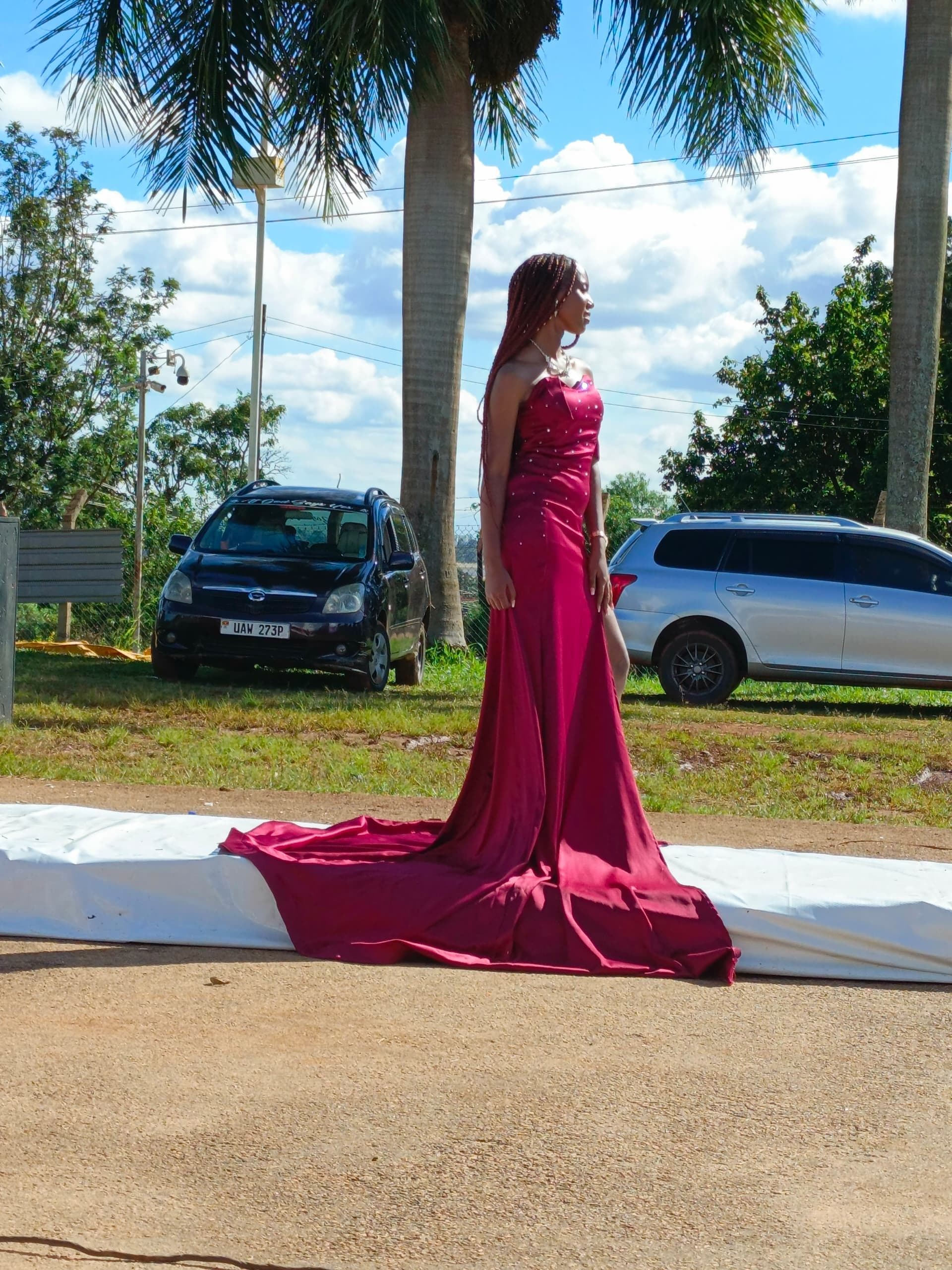 A model in a magenta gown walking an outdoor fashion show runway