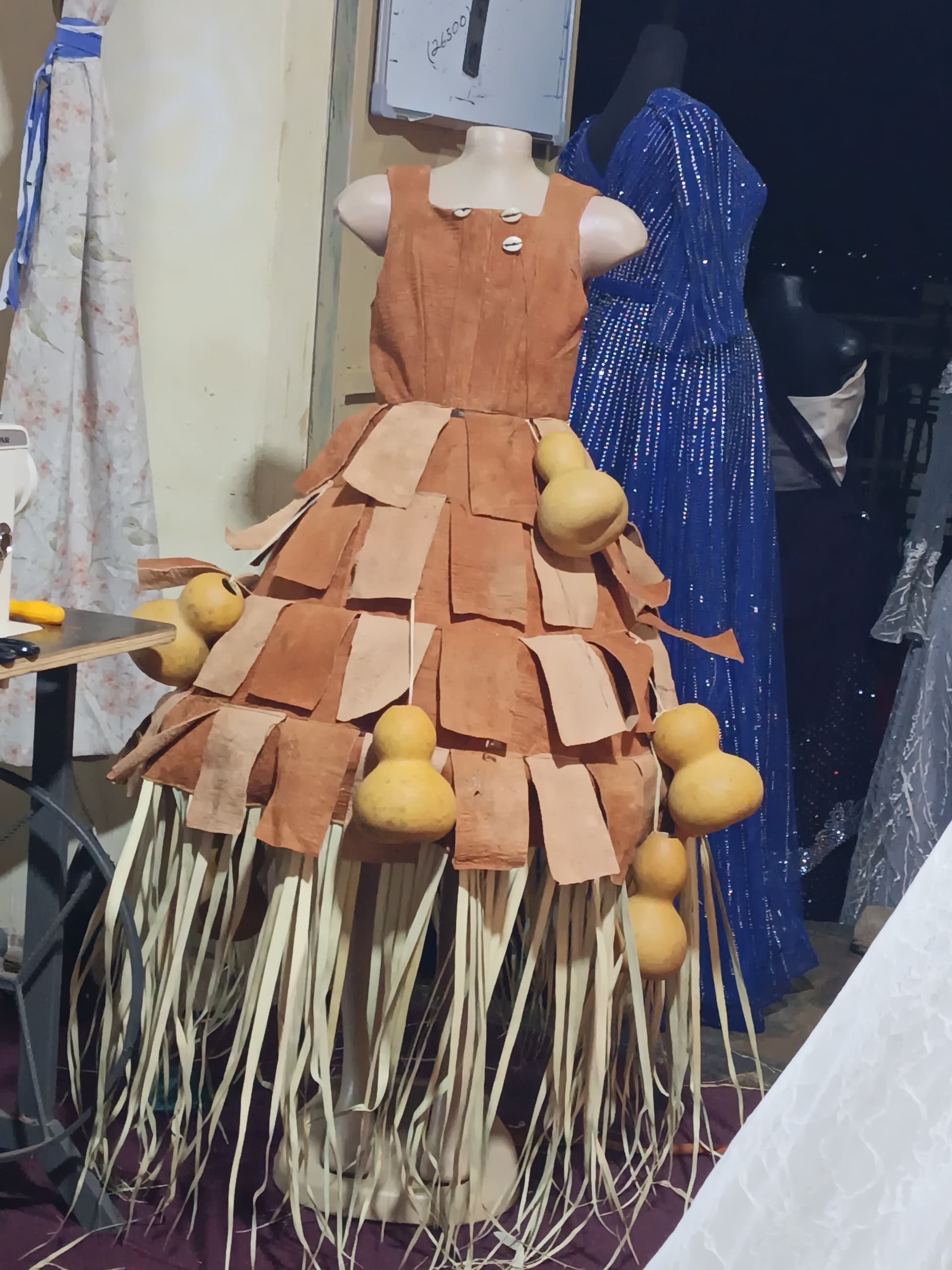 A handcrafted dress made from bark cloth and gourds displayed on a mannequin