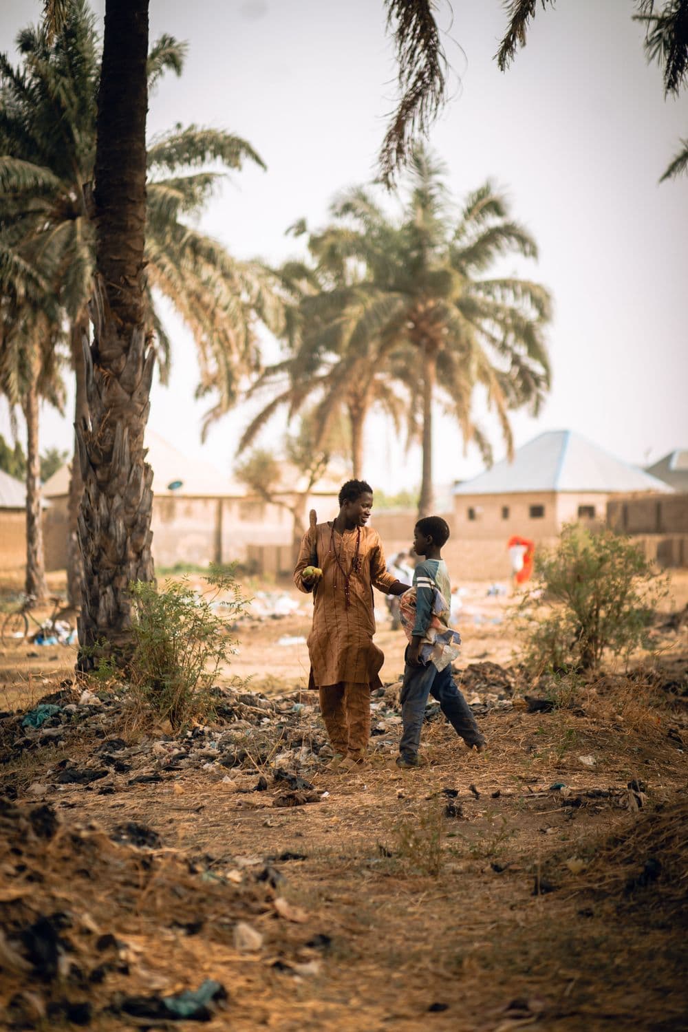 Two people walking together in a rural Ugandan village