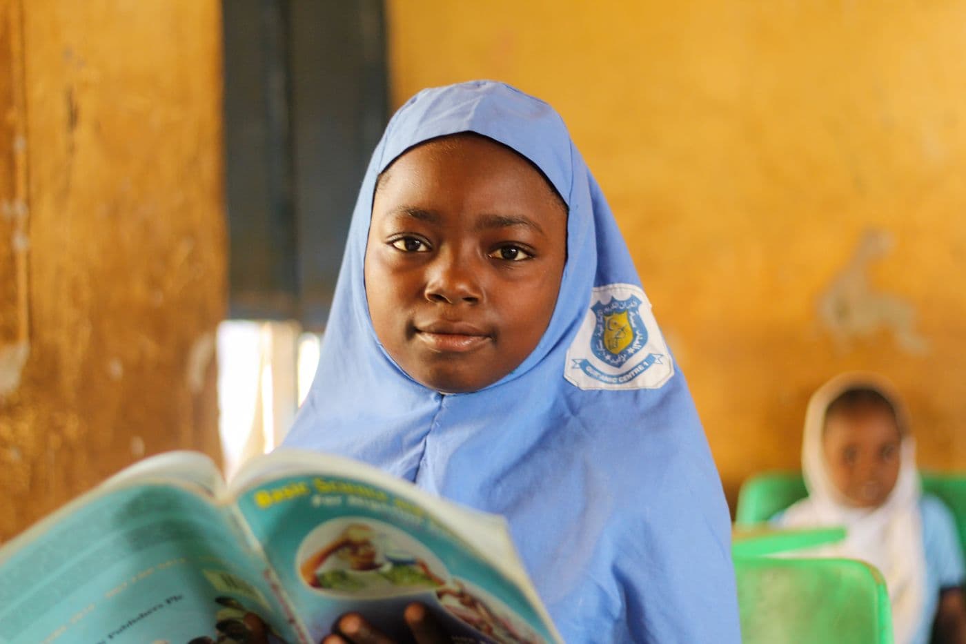 A young girl reading and smiling in class